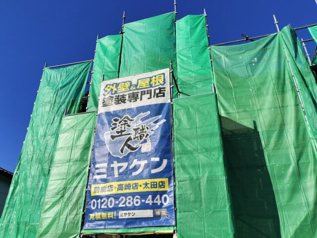 太田市矢場町の外壁塗装工事で建物に足場とメッシュシートを設置したミヤケンの施工現場と幟